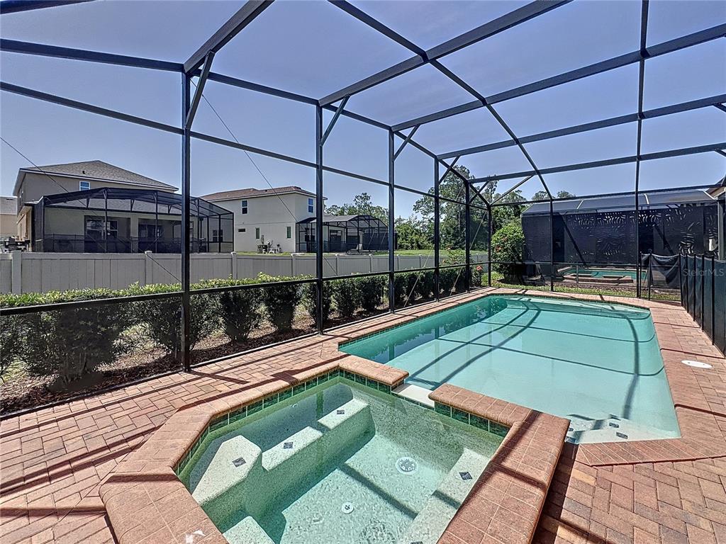 A screened-in patio features a rectangular swimming pool and a raised tiled spa — 1614 LIMA AVENUE, KISSIMMEE, FL