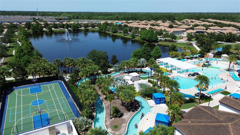 An aerial view shows a community pool with a lazy river, basketball court, and lake — 1614 LIMA AVENUE, KISSIMMEE, FL