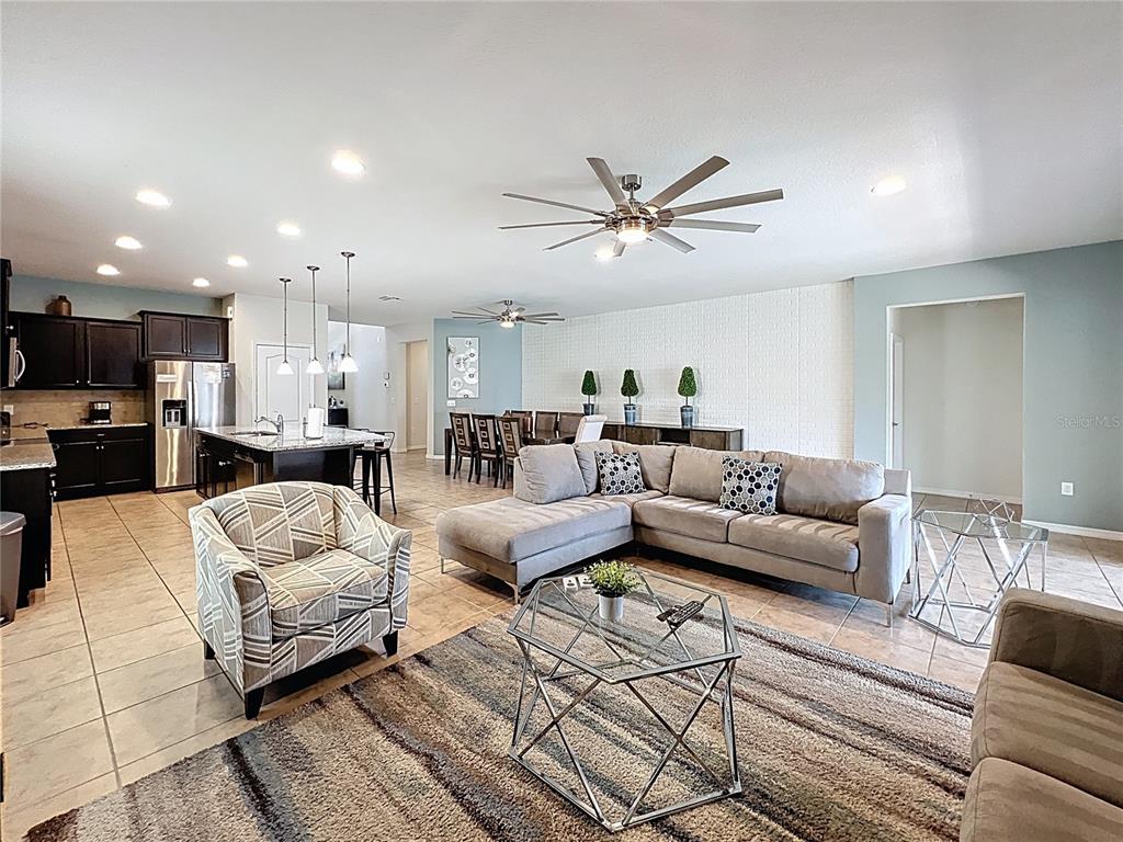 An open-concept living and dining area features tile flooring, a sectional sofa, and a kitchen — 1614 LIMA AVENUE, KISSIMMEE, FL