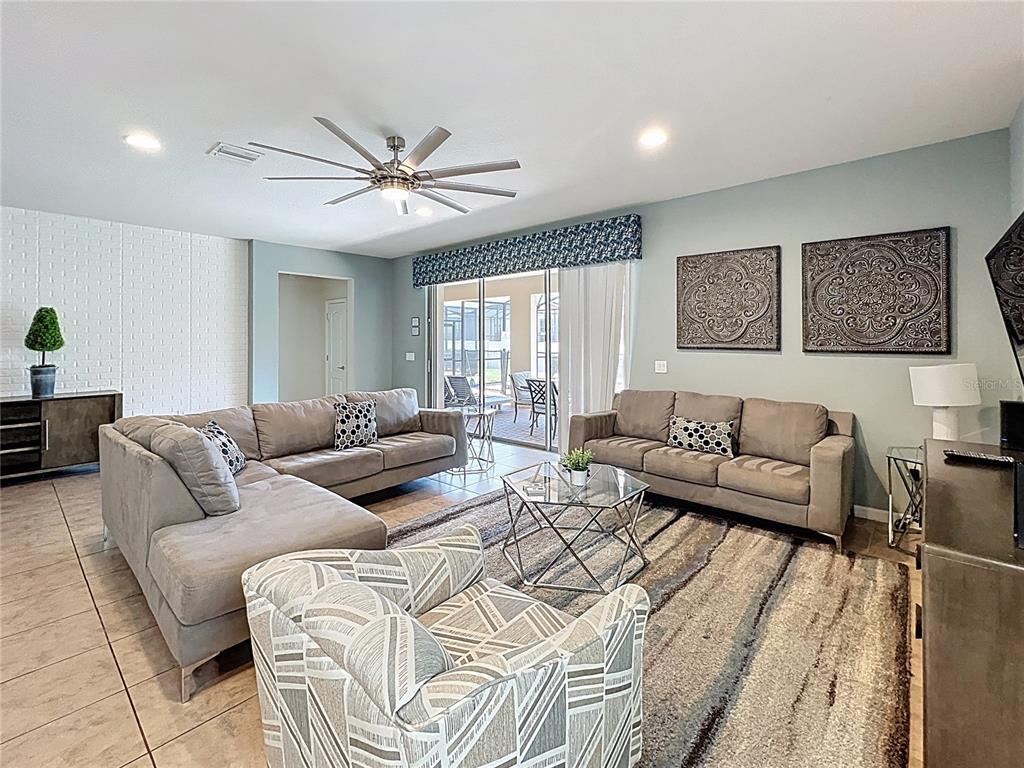 A living room features two gray sofas, a patterned armchair, and a glass coffee table — 1614 LIMA AVENUE, KISSIMMEE, FL
