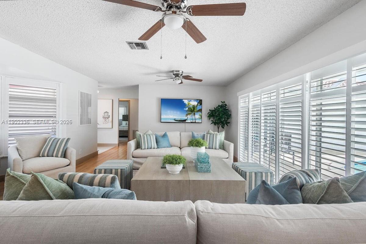 A living room features a sofa, armchairs, a coffee table, and ceiling fans — 1500 NW 45th St, Pompano Beach FL 33064, POMPANO BEACH, FL