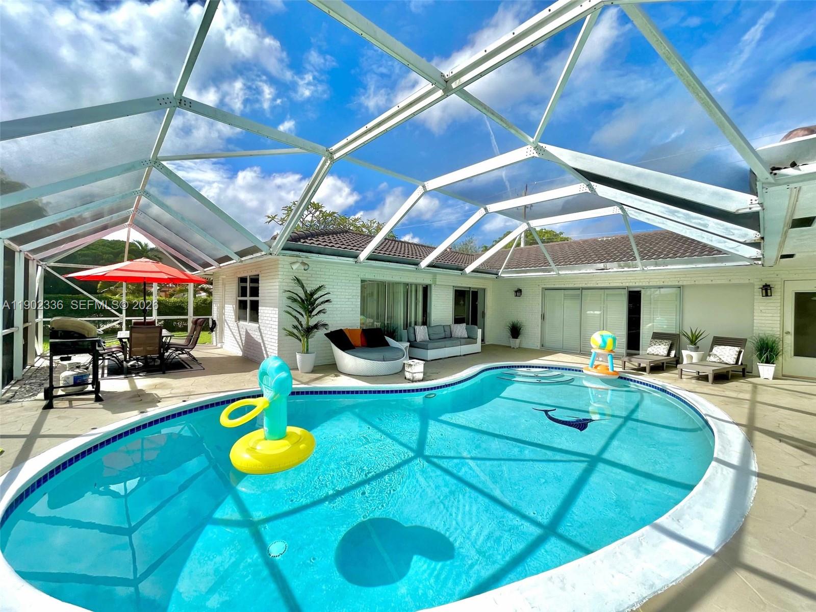 A screened-in patio features a swimming pool, outdoor seating, and a dining area — 1500 NW 45th St, Pompano Beach FL 33064, POMPANO BEACH, FL