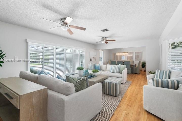 A living room features light-colored furniture, two ceiling fans, and wood-look flooring — 1500 NW 45th St, Pompano Beach FL 33064, POMPANO BEACH, FL