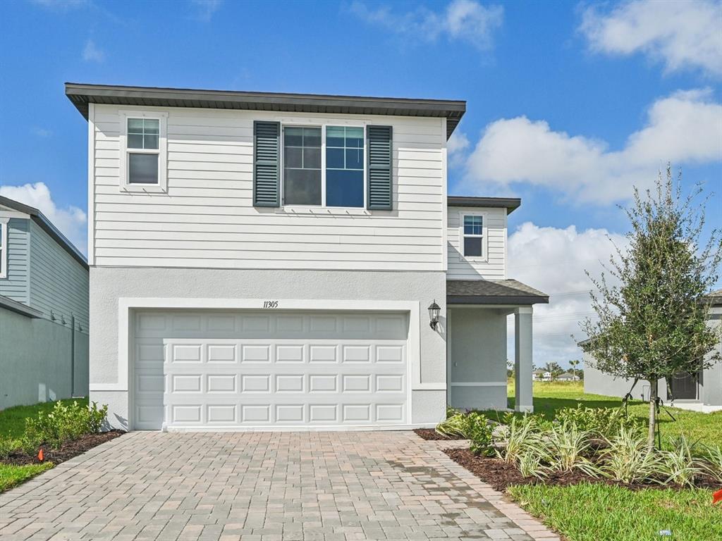 A two-story house with white horizontal siding, a two-car garage, and a paved driveway — 11305 BELLEWOOD TERRACE, PARRISH, FL
