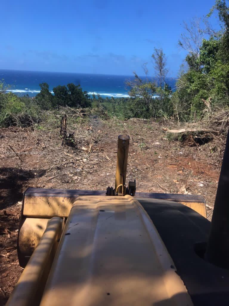A view from the operator's seat of heavy machinery overlooking a cleared lot and ocean — CARR 110 KM.HM 9.9 NW OCEAN VIEW 2794 SM, PR 00603, PR