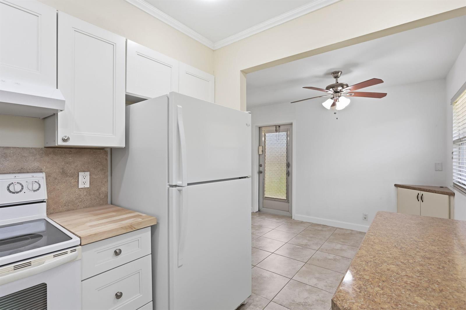 A kitchen with white cabinets, a white refrigerator, and a tiled dining area beyond — 164 Seville G, Delray Beach FL 33446, DELRAY BEACH, FL