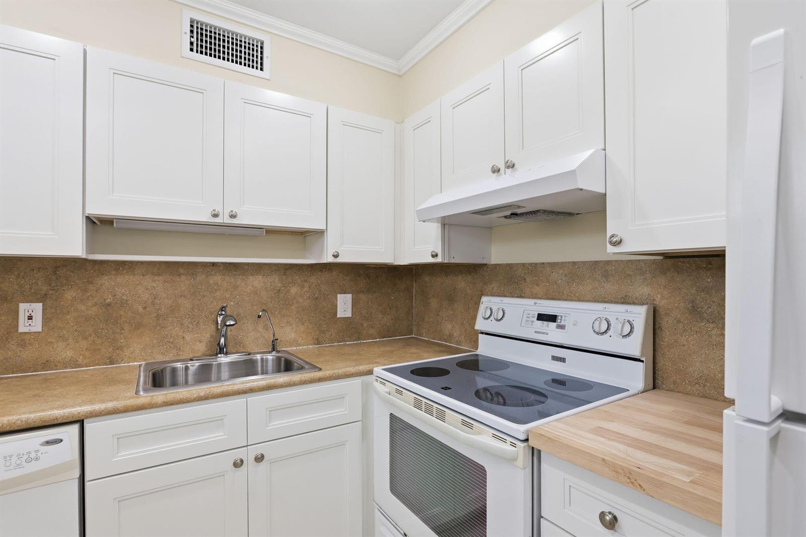 A kitchen with white cabinets, a stainless steel sink, and a white electric range — 164 Seville G, Delray Beach FL 33446, DELRAY BEACH, FL