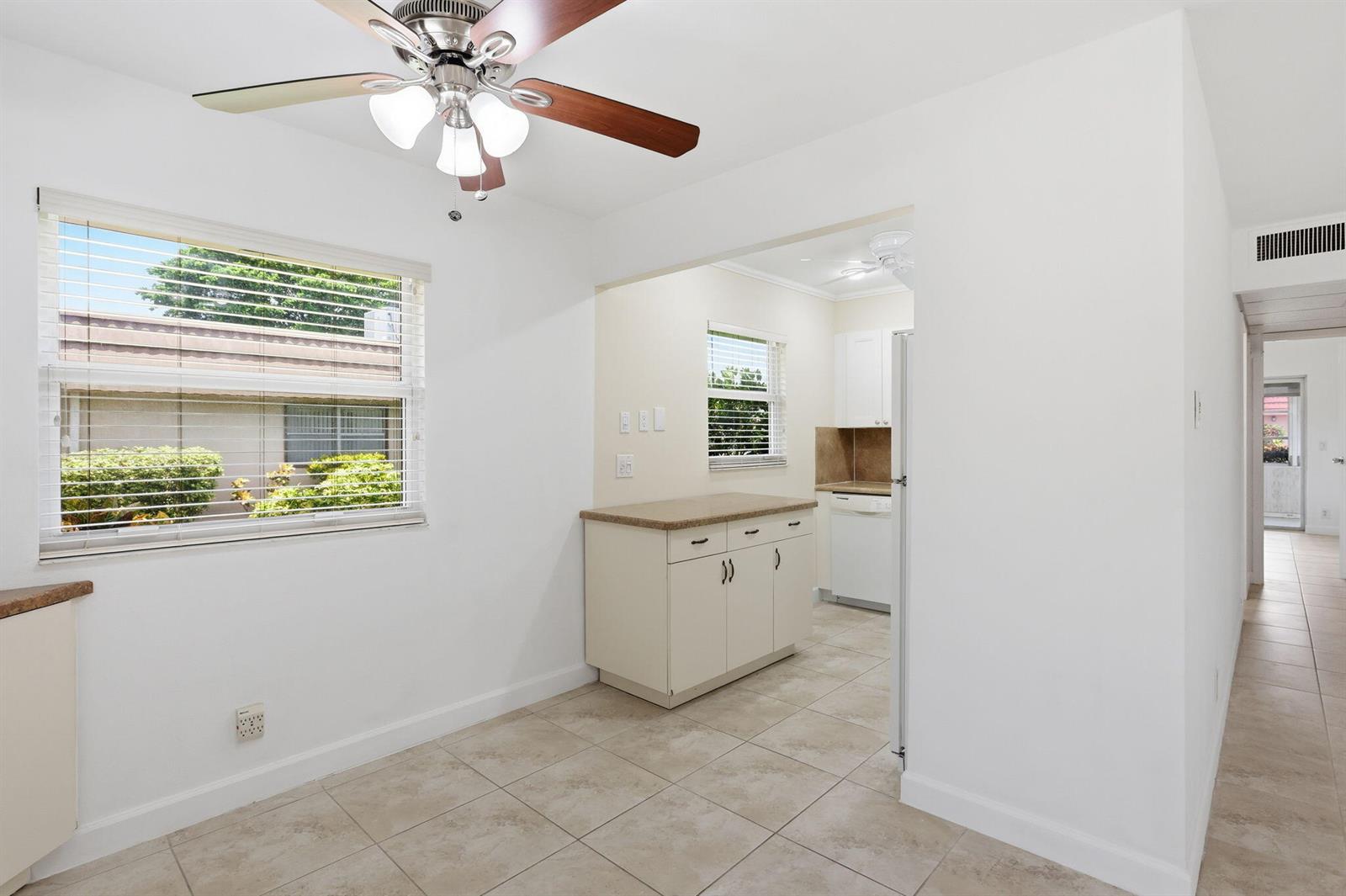 A dining area with tile floors and a ceiling fan opens into a small kitchen — 164 Seville G, Delray Beach FL 33446, DELRAY BEACH, FL