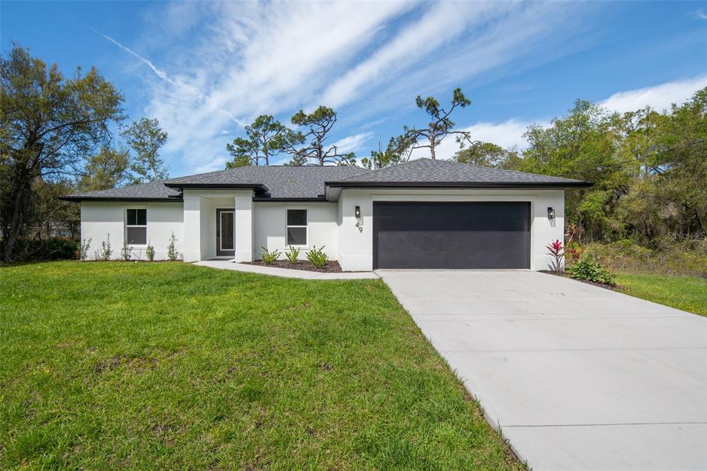A single-story white house with a dark garage door and a concrete driveway — 49 TROUTDALE STREET, PORT CHARLOTTE, FL