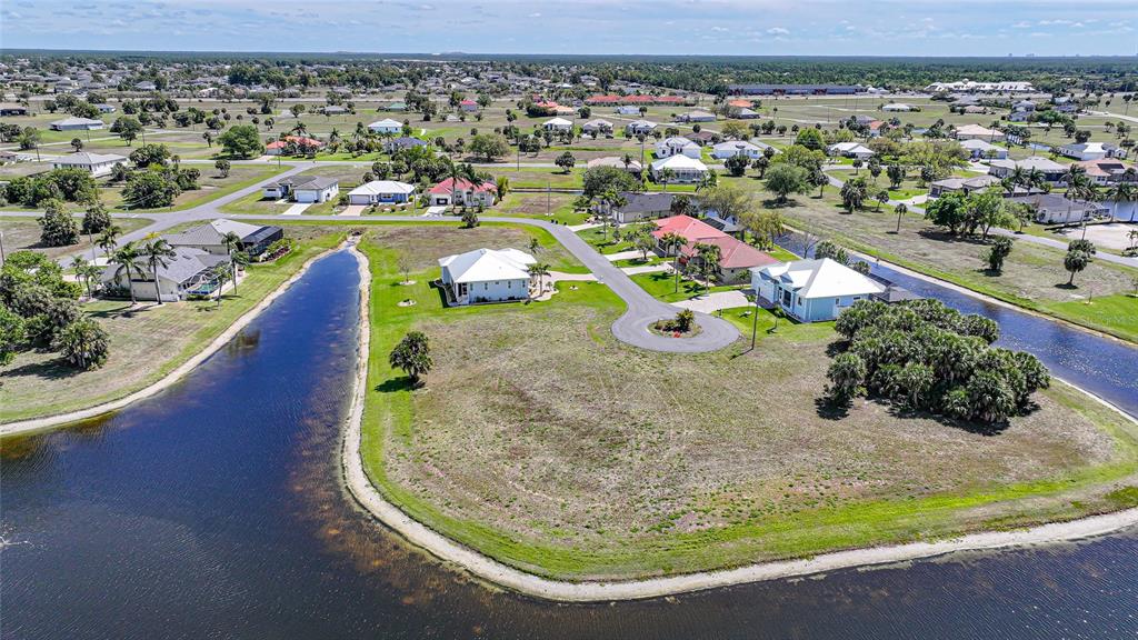 An aerial view shows several houses situated on a large lot surrounded by a lake — 16395 NOGALES COURT, PUNTA GORDA, FL
