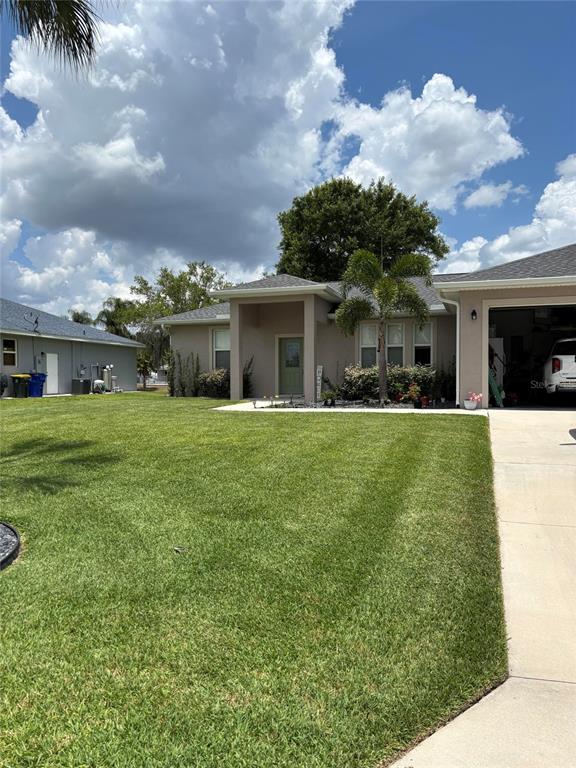 A single-story house with a green front door, a palm tree, and a concrete driveway — 121 DAISY LANE, LAKE PLACID, FL