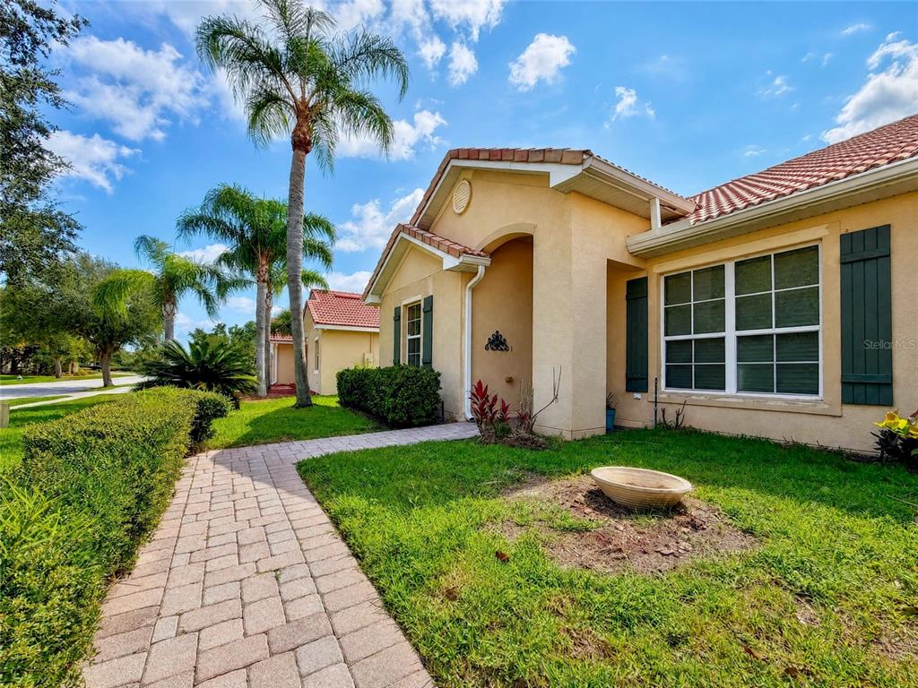 A paved walkway leads to the entrance of a tan house with a tiled roof — 3505 FOREST PARK DRIVE, KISSIMMEE, FL