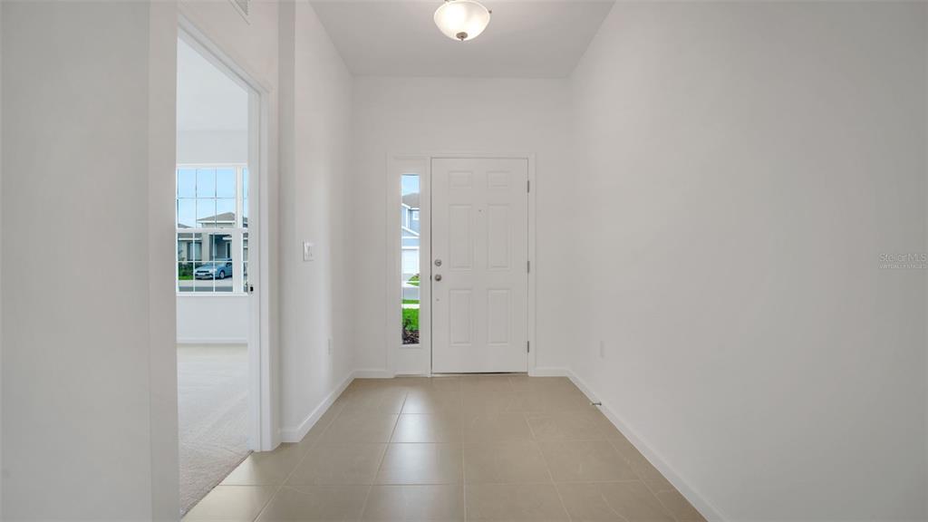 A bright entryway features white walls, light tile flooring, and a white front door — 4094 PENELOPE AVENUE, LAKE WALES, FL