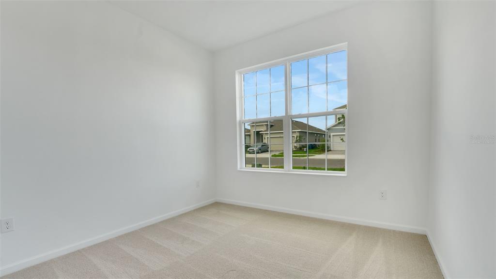 An empty room with white walls, beige carpeting, and a window overlooking a suburban street — 4094 PENELOPE AVENUE, LAKE WALES, FL