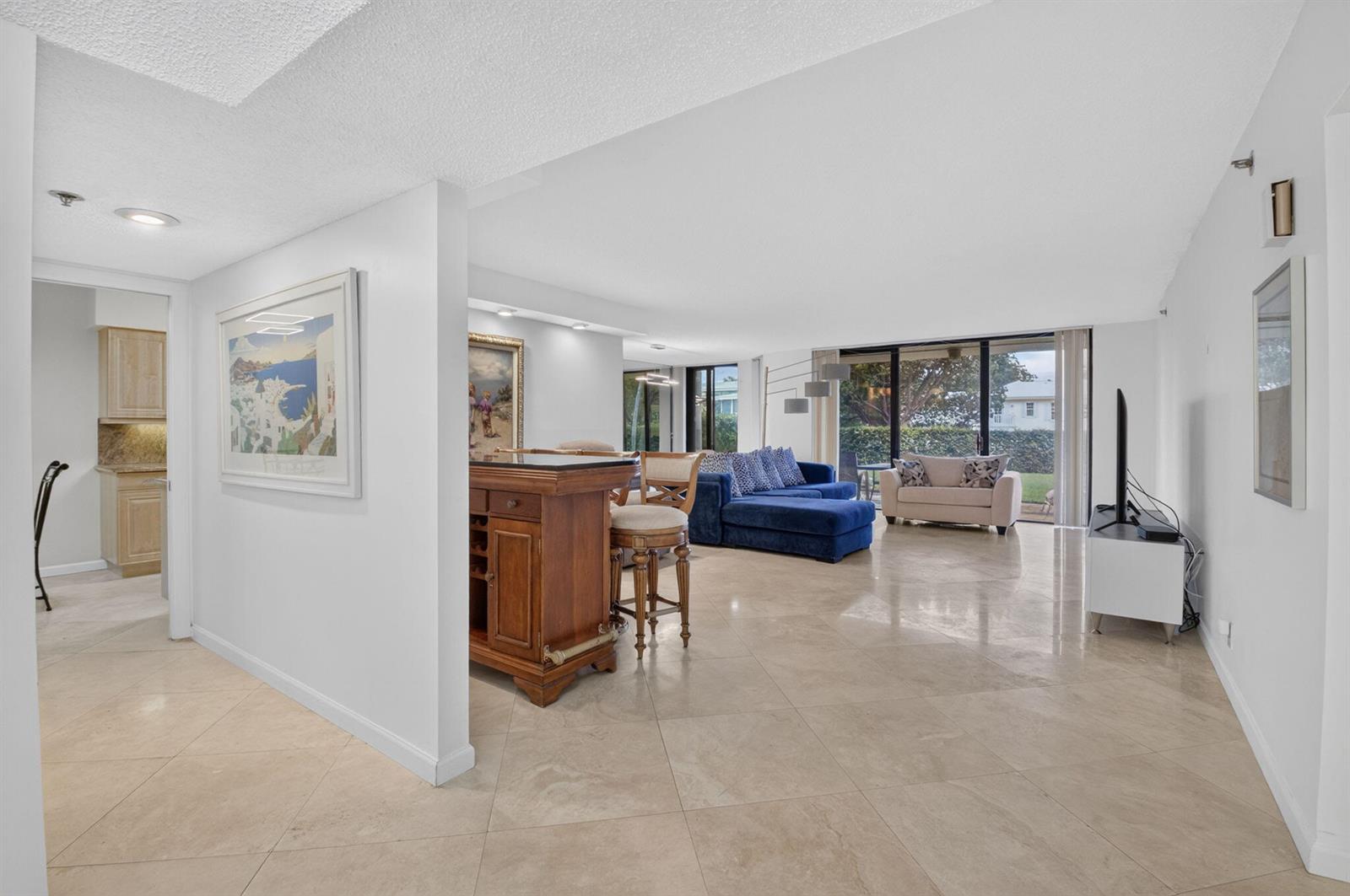 A living room with tile floors, a wooden bar, and a blue sectional sofa — 1401 S Ocean Boulevard # 1060, Boca Raton FL 33432, BOCA RATON, FL