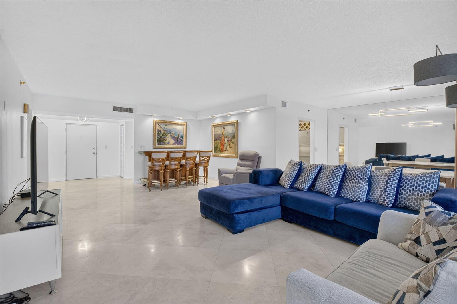 A living room features a blue sectional sofa, a home bar, and light tile flooring — 1401 S Ocean Boulevard # 1060, Boca Raton FL 33432, BOCA RATON, FL