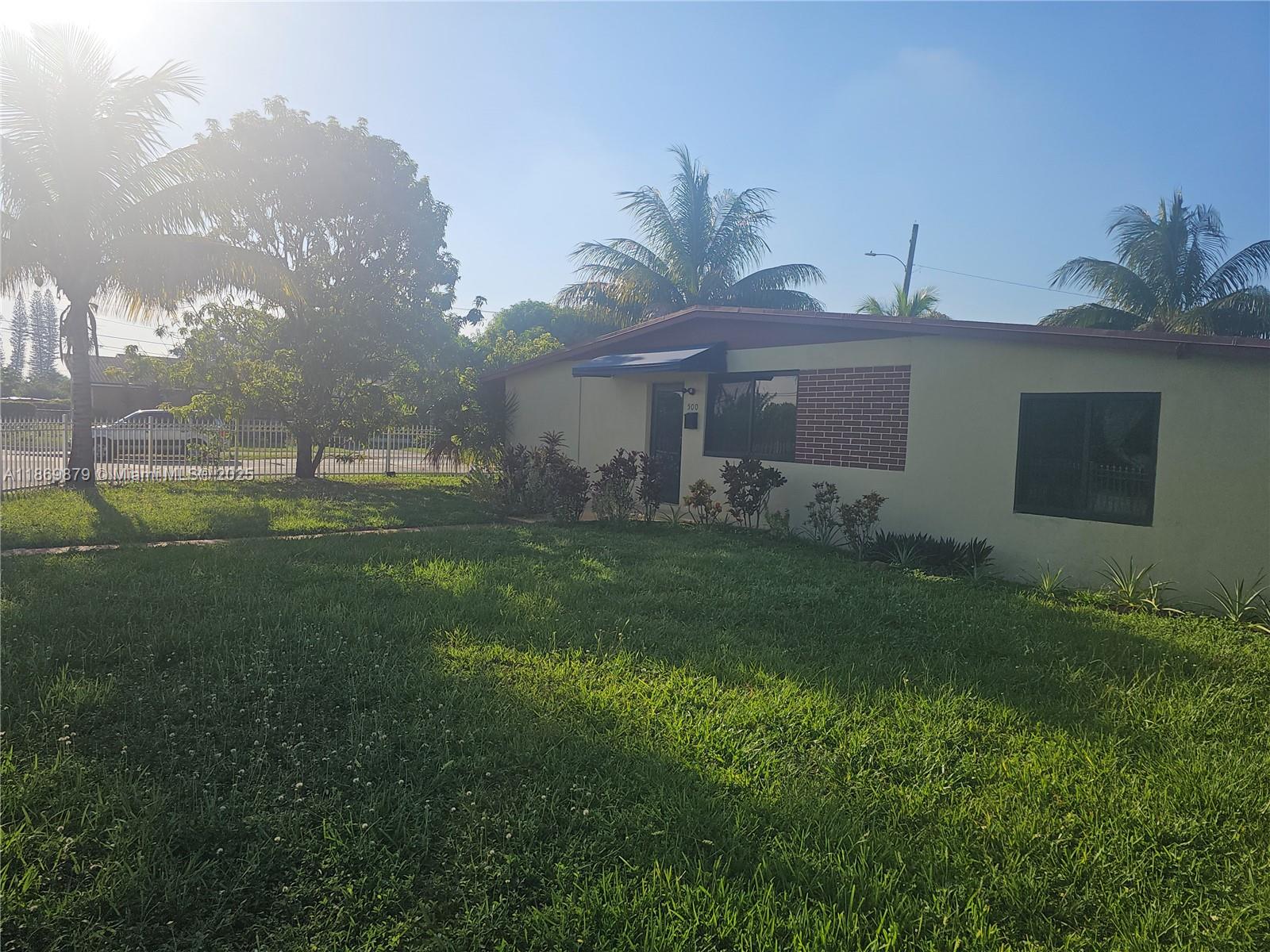 A single-story house with a yellow exterior, brick accent, and a front lawn with palms — 500 NW 199th St, Miami Gardens FL 33169, MIAMI GARDENS, FL