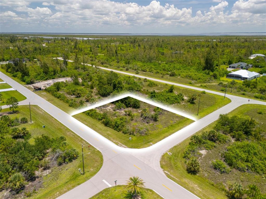 An aerial view shows a vacant, corner residential lot surrounded by roads and vegetation — 10536 ST PAUL DRIVE, PORT CHARLOTTE, FL