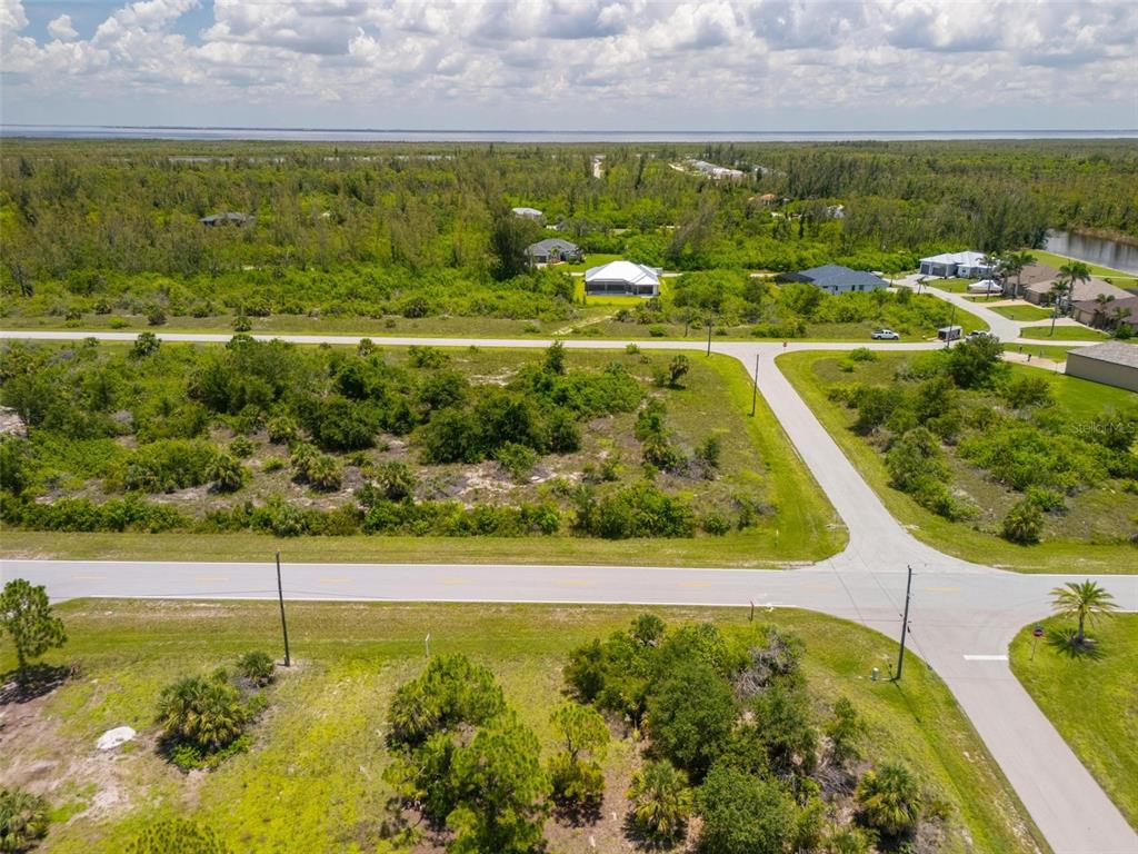 An aerial view shows a vacant lot at a road intersection near a wooded area — 10536 ST PAUL DRIVE, PORT CHARLOTTE, FL