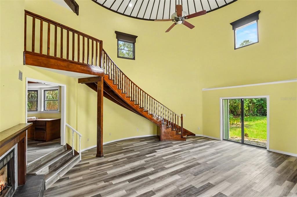 A living room features a wooden staircase, light yellow walls, and wood-look flooring — 888 HARMONY LANE, ENGLEWOOD, FL