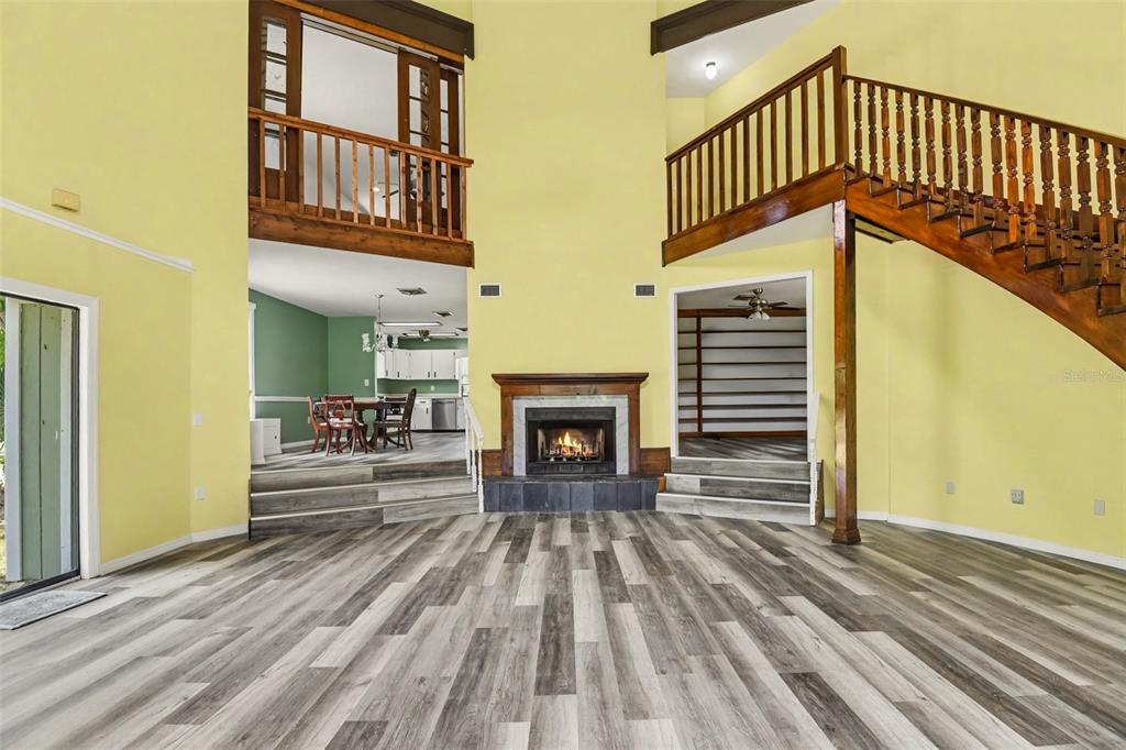 A living room with a fireplace, wood-look flooring, and a staircase leading to a loft — 888 HARMONY LANE, ENGLEWOOD, FL