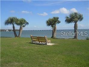 A wooden bench sits on a grassy lawn overlooking a body of water with palm trees — 585 SKY HARBOR DRIVE UNIT 126, CLEARWATER, FL