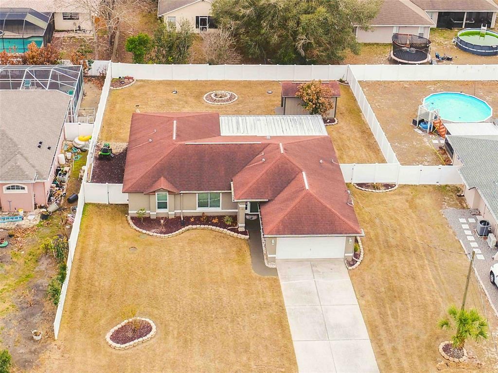An aerial view shows a single-story house with a red roof, driveway, and fenced yard — 11244 REDGATE STREET, SPRING HILL, FL