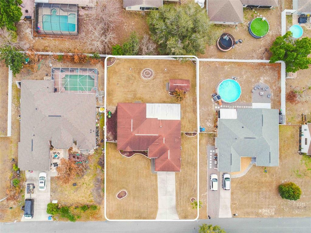 An aerial view shows a single-family home with a red roof and a fenced backyard — 11244 REDGATE STREET, SPRING HILL, FL