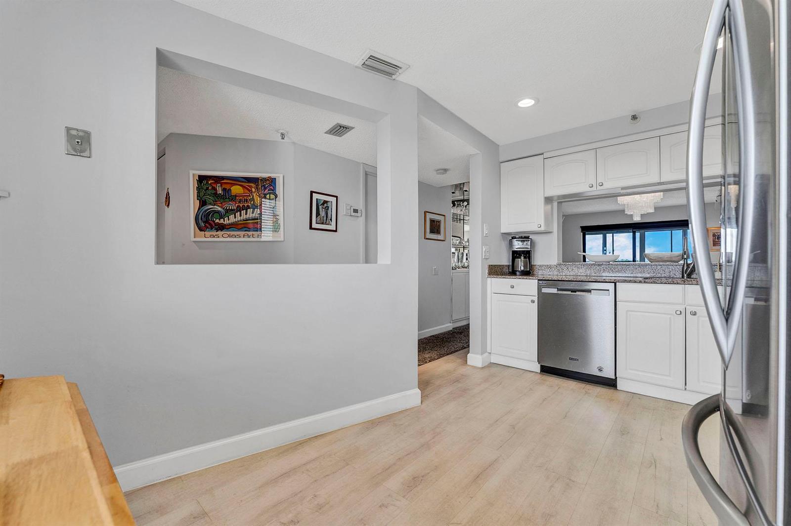 A kitchen with white cabinets, stainless steel appliances, and a pass-through window to another room — 14475 Strathmore Lane # 703, Delray Beach FL 33446, DELRAY BEACH, FL