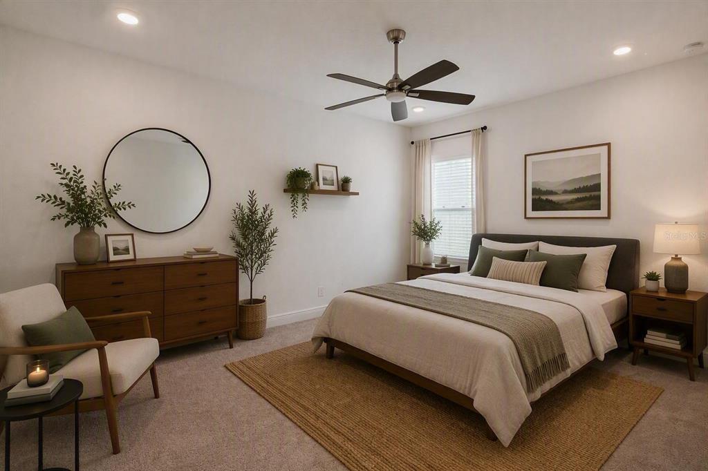 A bedroom features a bed, dresser, armchair, and ceiling fan with neutral decor and carpet — 1699 MEADOWLARK DRIVE, DELTONA, FL