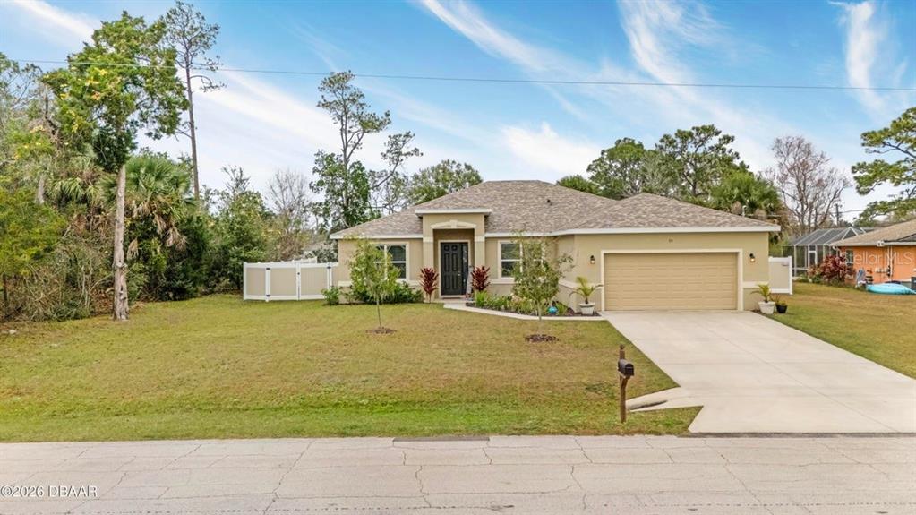 A single-story house with a tan stucco exterior, a two-car garage, and a front lawn — 55 PRESIDENTIAL LANE, PALM COAST, FL
