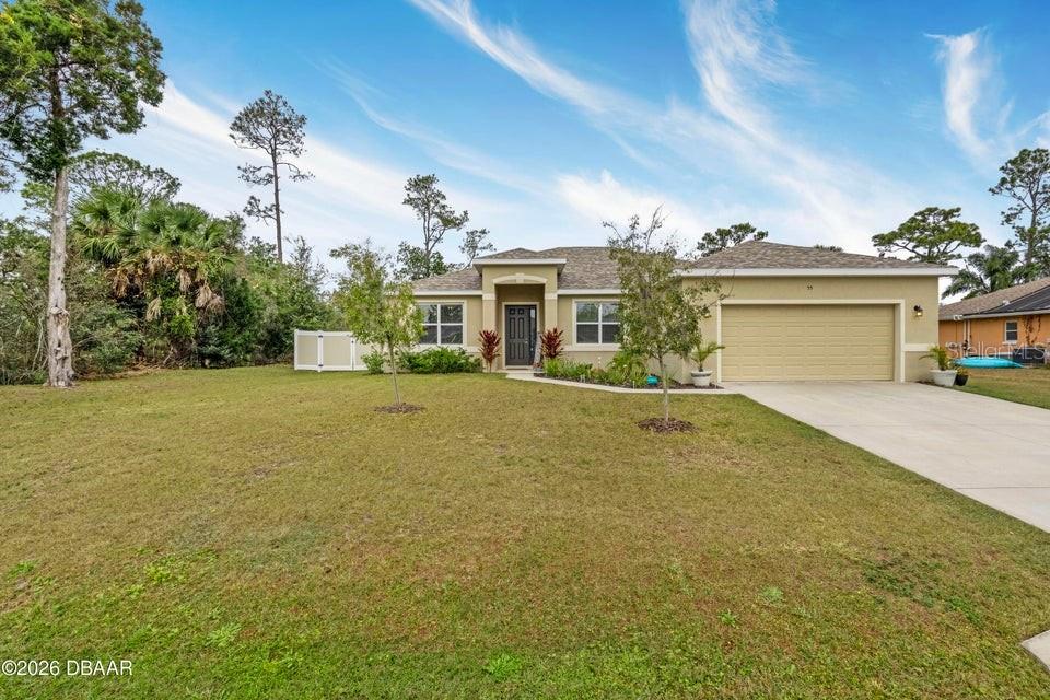 A single-story house with a beige stucco exterior, a two-car garage, and a front lawn — 55 PRESIDENTIAL LANE, PALM COAST, FL