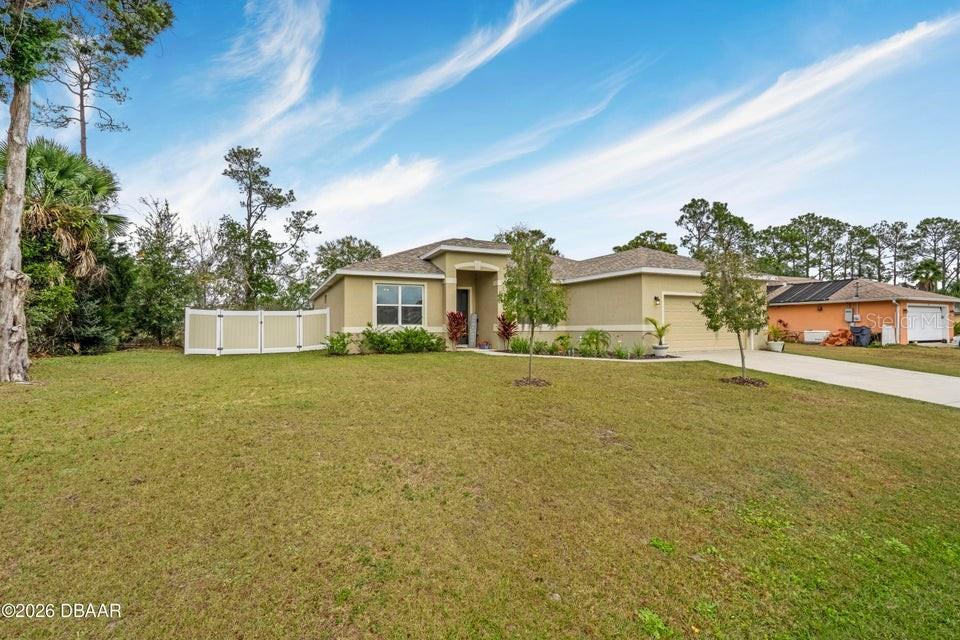 A single-story tan house with a two-car garage and a white vinyl privacy fence — 55 PRESIDENTIAL LANE, PALM COAST, FL
