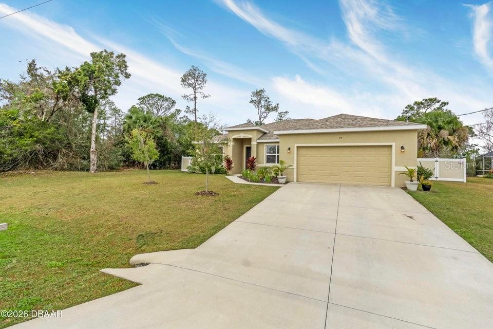 A single-story house with a beige stucco exterior, a two-car garage, and a concrete driveway — 55 PRESIDENTIAL LANE, PALM COAST, FL