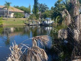 A boat is docked at a wooden pier on a canal behind a residential house — 14272 AURELLA CIRCLE, PORT CHARLOTTE, FL