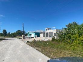 A newly constructed house with a light blue exterior stands along a gravel road — 14272 AURELLA CIRCLE, PORT CHARLOTTE, FL