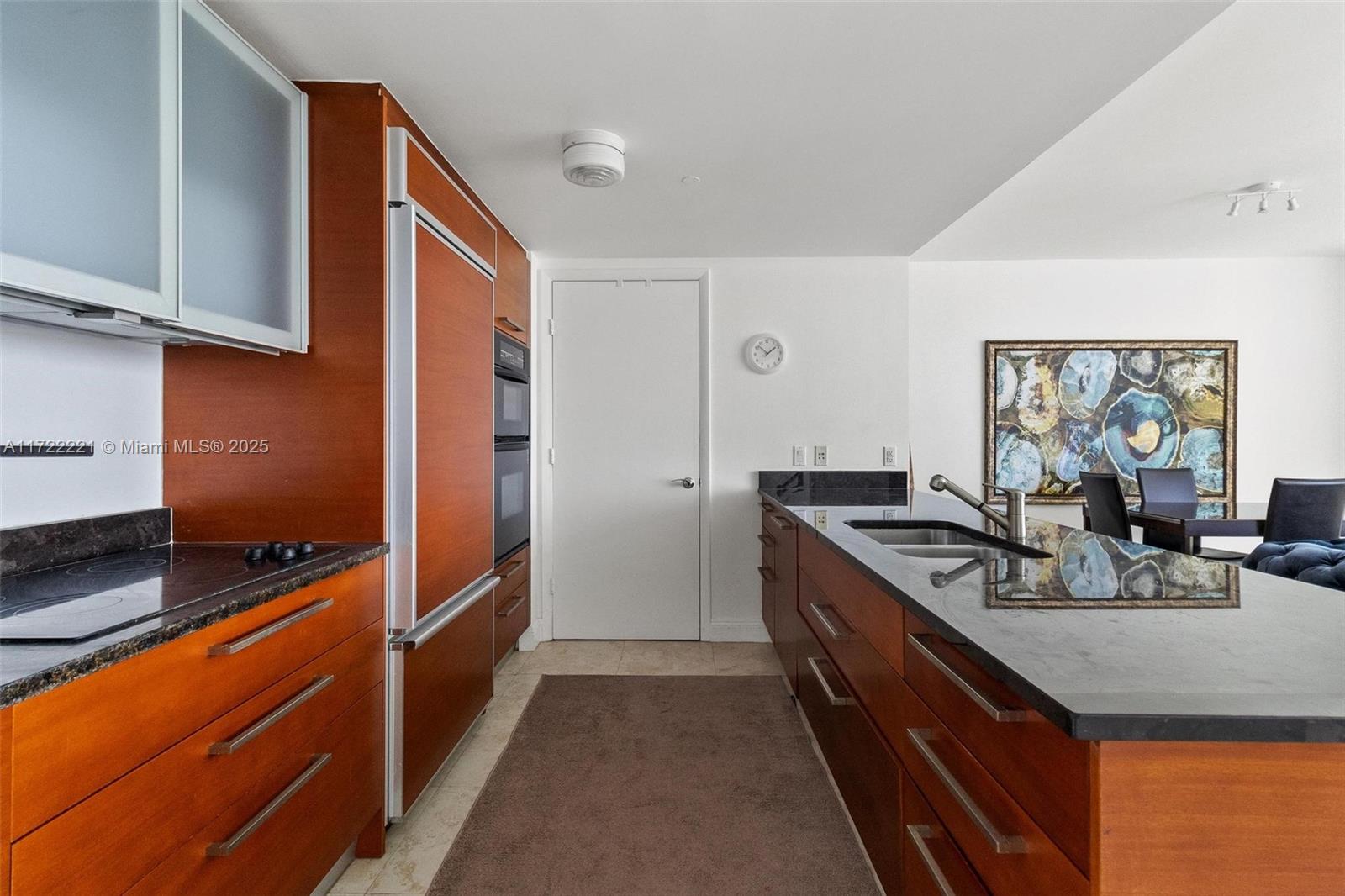 A kitchen features wood cabinetry, dark granite countertops, stainless steel appliances, and a central island — 1830 S Ocean Dr # 4507, Hallandale Beach FL 33009, HALLANDALE BEACH, FL