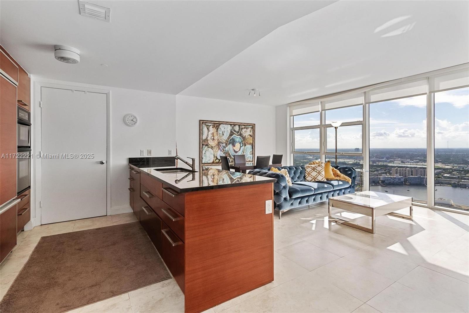 A modern open-concept apartment features a kitchen island, blue tufted sofa, and floor-to-ceiling windows — 1830 S Ocean Dr # 4507, Hallandale Beach FL 33009, HALLANDALE BEACH, FL