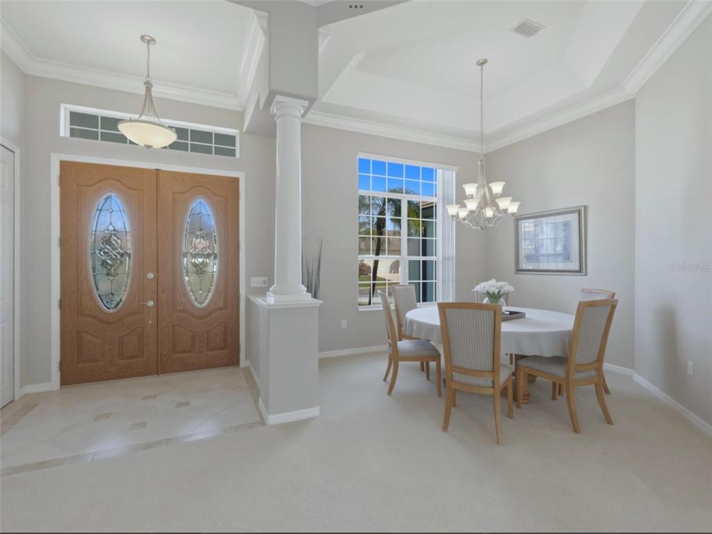 A dining area with a round table, chandelier, and a view of the front entryway — 4967 WILD DAISY LANE, VENICE, FL