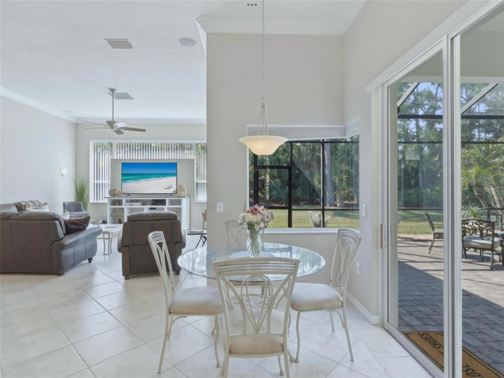 A dining area with a glass table and chairs sits adjacent to a living room — 4967 WILD DAISY LANE, VENICE, FL