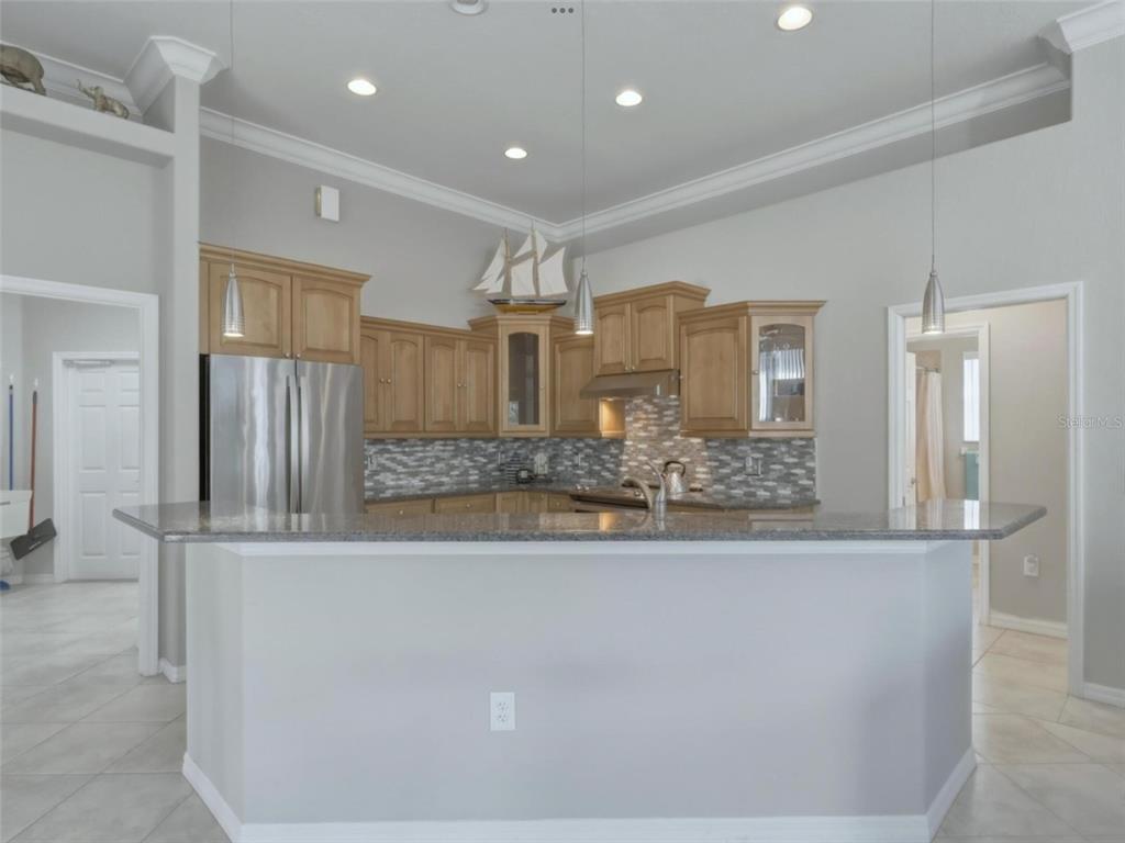 A kitchen with light wood cabinets, granite countertops, stainless steel appliances, and a breakfast bar — 4967 WILD DAISY LANE, VENICE, FL