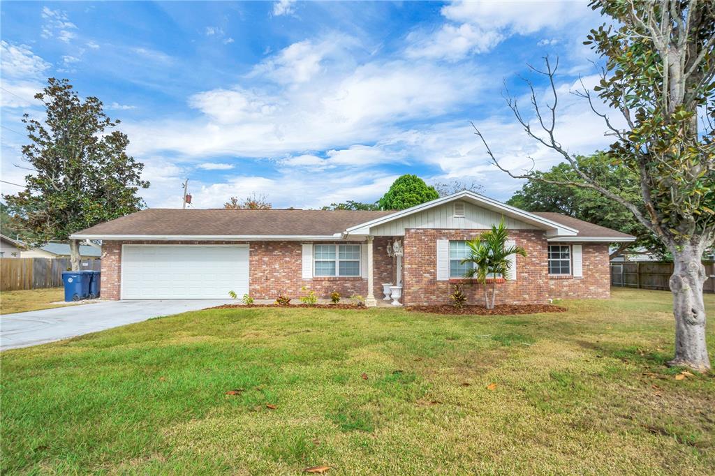 A single-story brick house with a two-car garage and a front lawn under a blue sky — 1206 SUSAN LANE, AUBURNDALE, FL