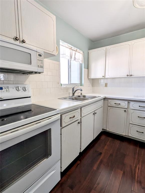 A kitchen features white cabinets, a white stove, a double sink, and dark wood flooring — 5922 GARDEN LANE UNIT A31, BRADENTON, FL