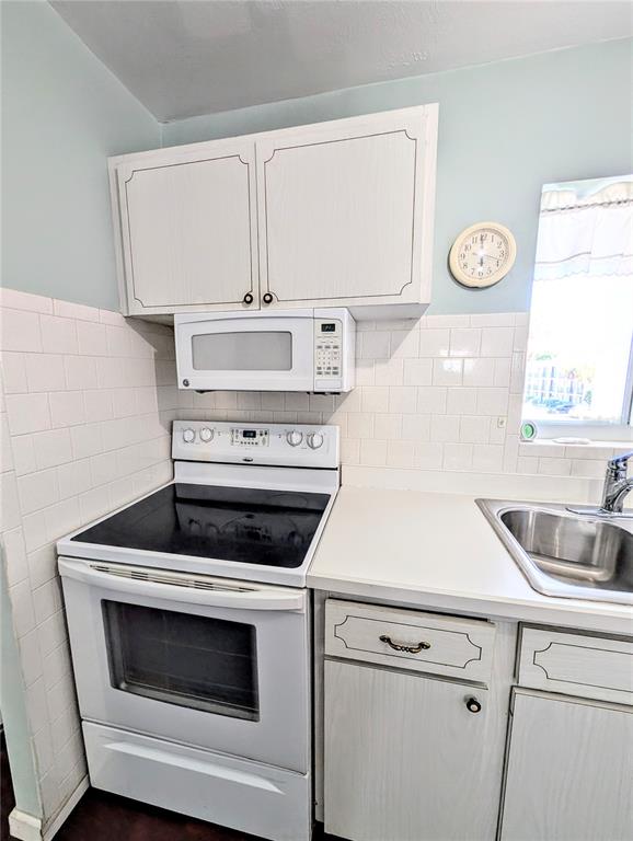 A kitchen features white cabinets, a microwave, an electric stove, and a stainless steel sink — 5922 GARDEN LANE UNIT A31, BRADENTON, FL