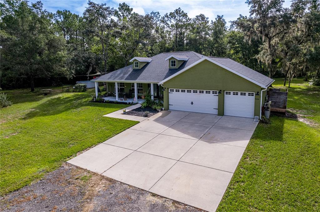 An exterior view of a green house with a two-car garage and a front porch — 9230 SIKES COW PEN ROAD, BROOKSVILLE, FL
