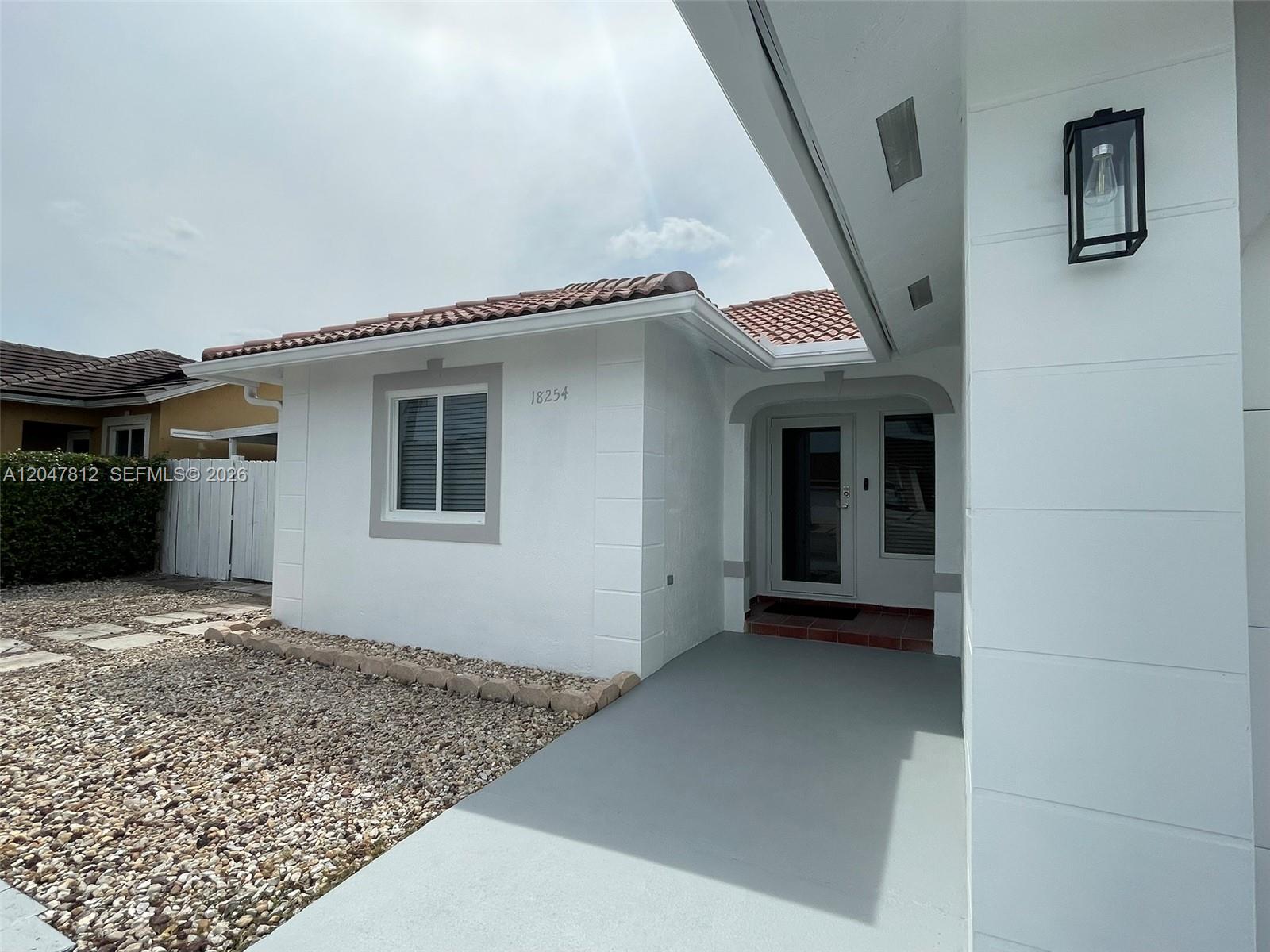 A white house exterior features a gray walkway, a tiled roof, and a front entrance — 18254 SW 143rd Pl # 0, Miami FL 33177, MIAMI, FL