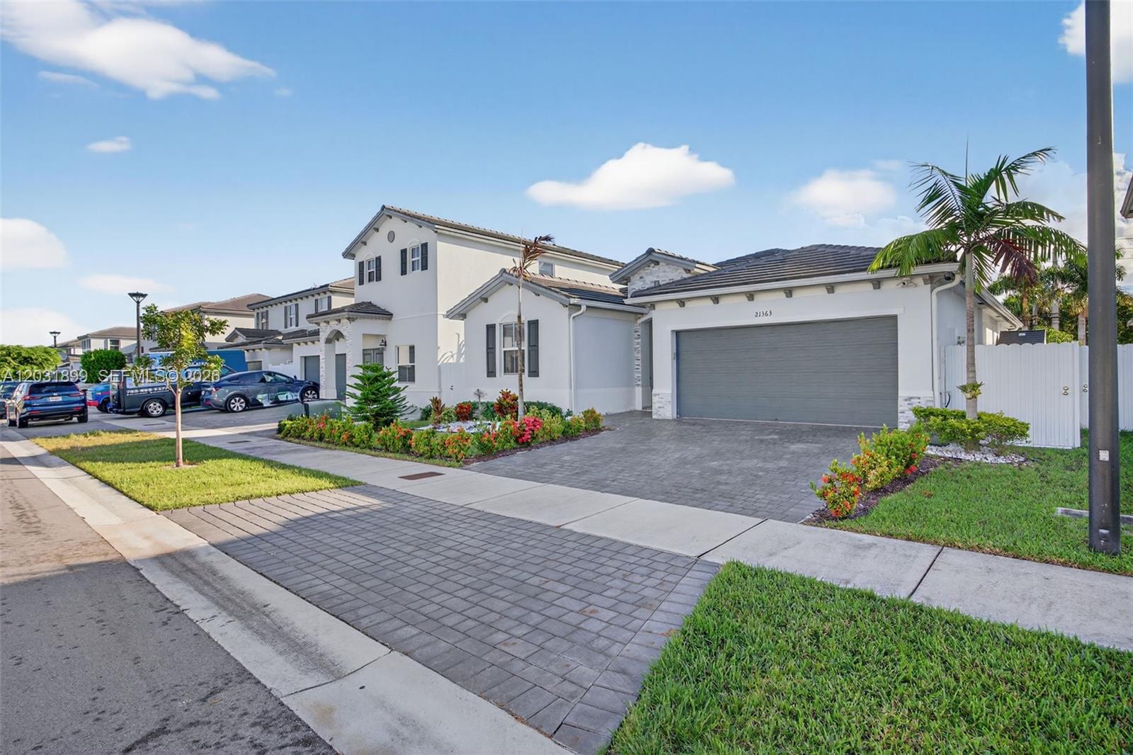 A two-story suburban house features a gray garage, paved driveway, and landscaped front yard — 21363 SW 127th Ct, Miami FL 33177, MIAMI, FL