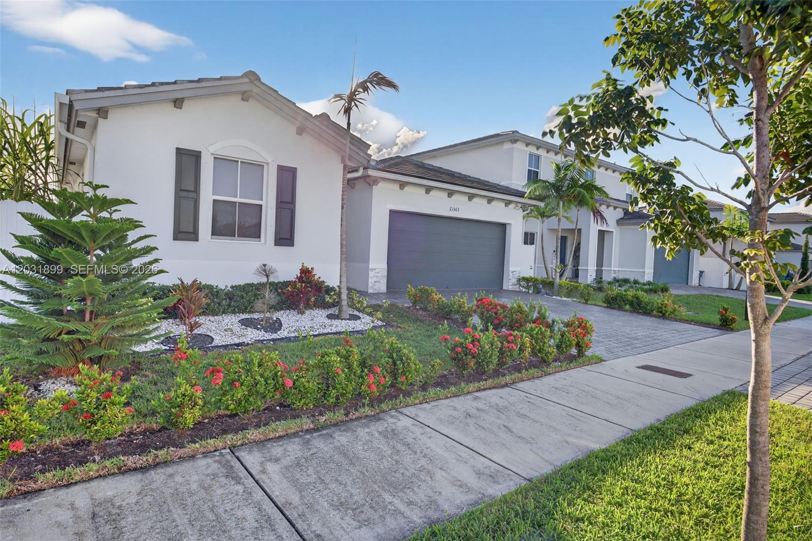 A single-story house with a gray garage, white stucco walls, and landscaped front yard — 21363 SW 127th Ct, Miami FL 33177, MIAMI, FL