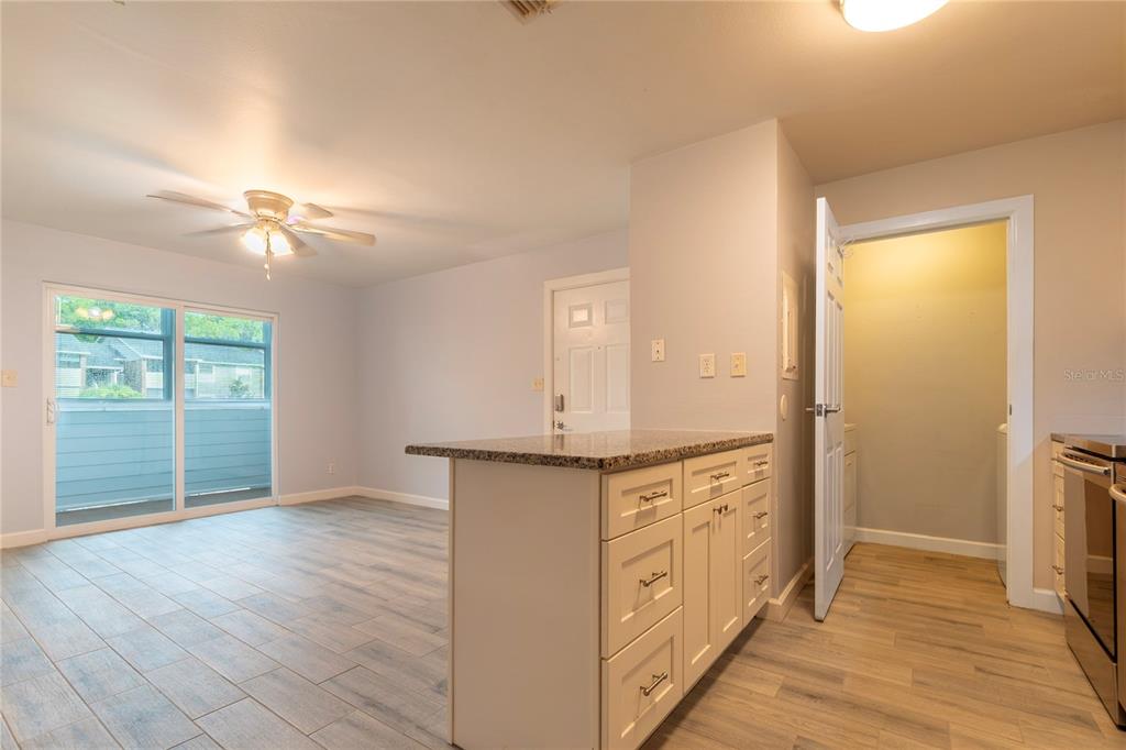 A kitchen island with granite countertops overlooks a living area with sliding glass doors — 1400 GANDY BOULEVARD N UNIT 1010, ST PETERSBURG, FL
