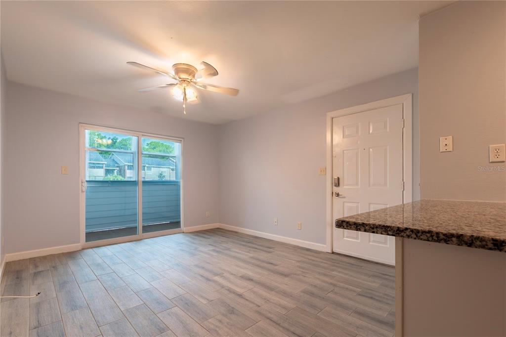 A living room features light wood-look tile flooring, a ceiling fan, and a sliding glass door — 1400 GANDY BOULEVARD N UNIT 1010, ST PETERSBURG, FL